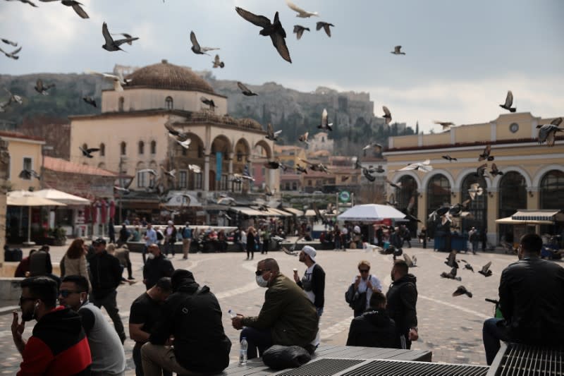 A man wears a protective mask as he sits on Monastiraki square in Athens