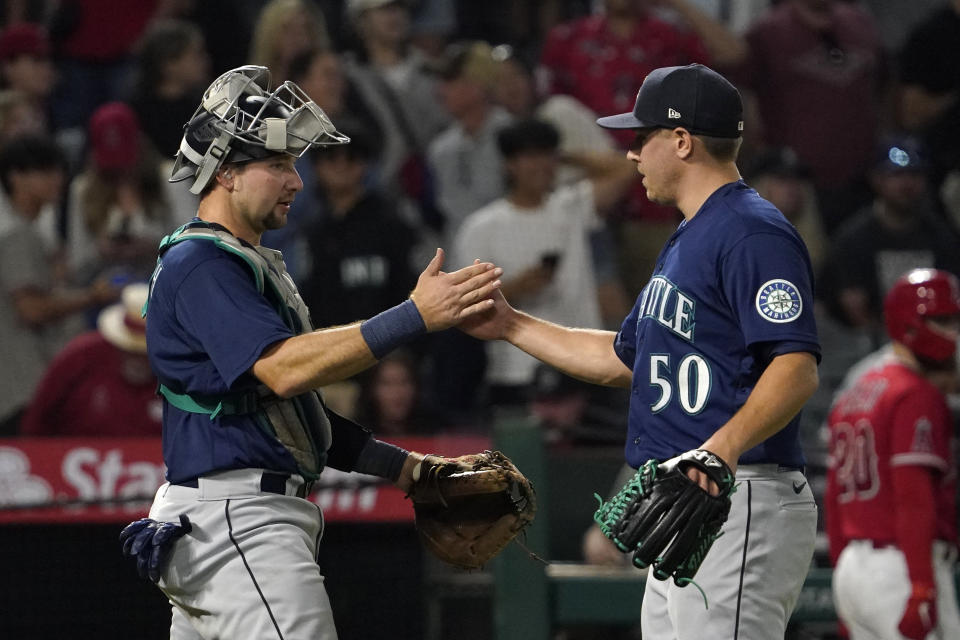 Seattle Mariners catcher Cal Raleigh, left, and relief pitcher Erik Swanson congratulate each other after the Mariners defeated the Los Angeles Angels 5-3 in a baseball game Saturday, June 25, 2022, in Anaheim, Calif. (AP Photo/Mark J. Terrill)