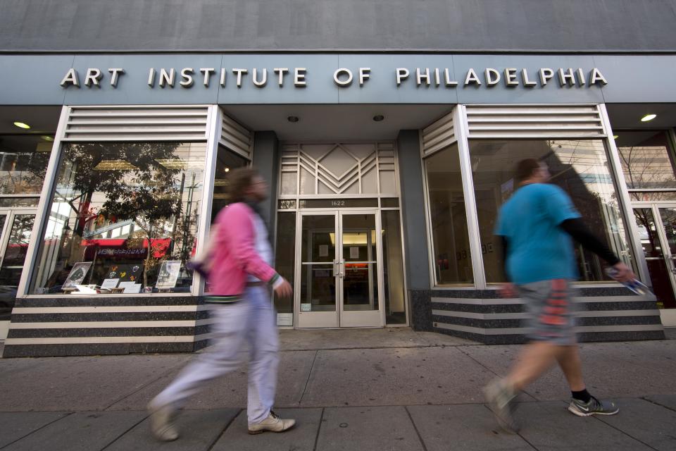 People walk past the Art Institute of Philadelphia operated by the Education Management Corporation on Monday, Nov. 16, 2015, in Philadelphia. The Obama administration has reached a $95.5 million settlement with a Pittsburgh firm that runs for-profit trade schools and colleges. The Justice Department settlement resolves allegations that Education Management Corporation used enrollment incentives to pay its recruiters and exaggerated its career-placement ability. (AP Photo/Matt Rourke)