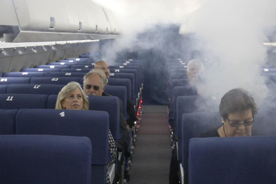 FAA employees participate in a demonstration of an airline cabin filling with smoke, in a simulator at the FAA Civil Aerospace Medical Institute in the Mike Monroney Aeronautical Center, Thursday, Oct. 17, 2019, in Oklahoma City. Federal researchers, using 720 volunteers in Oklahoma City, will test whether smaller seats and crowded rows slow down airline emergency evacuations. (AP Photo/Sue Ogrocki)