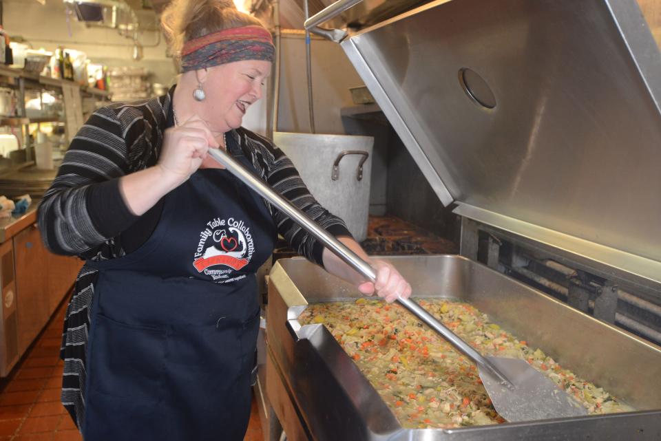 Jeni Wheeler uses a paddle to stir up 15 gallons of her Jeni's Joy 12 vegetable chicken soup at the Family Table Collaborative in South Yarmouth. The Collaborative will be sending out 500 meals across the Cape for Thanksgiving.