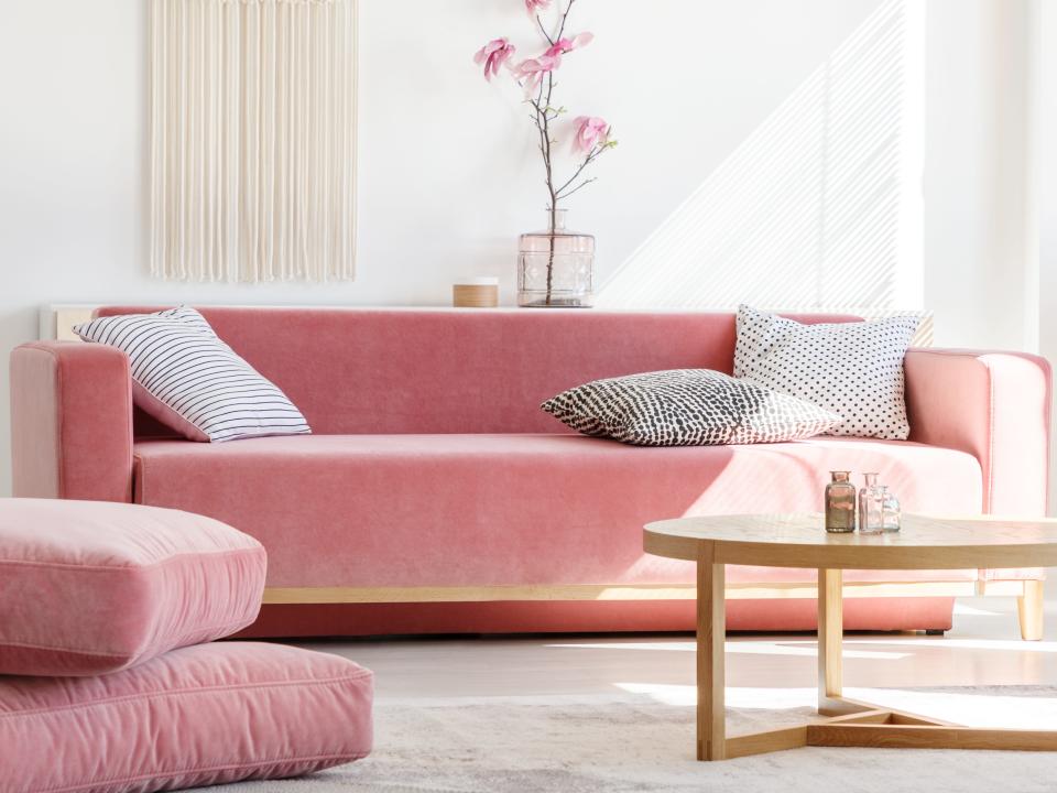 Pink pastel couch and wooden table with yellow chair to right