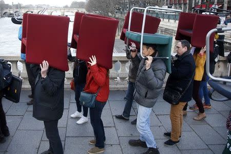 Demonstrators carry chairs that were stolen from bank offices in France to protest against a banking system and tax fraud, as they gather on a bridge near the courts in Paris, France, February 8, 2016. REUTERS/Charles Platiau