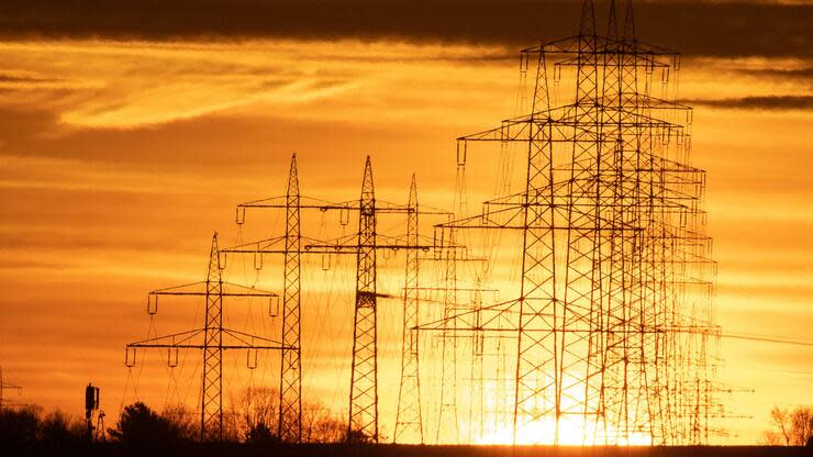 Strommasten stehen am Morgen bei Sonnenaufgang vor dem orange eingefärbten Himmel in Schwieberdingen, Baden-Württemberg. Foto: dpa