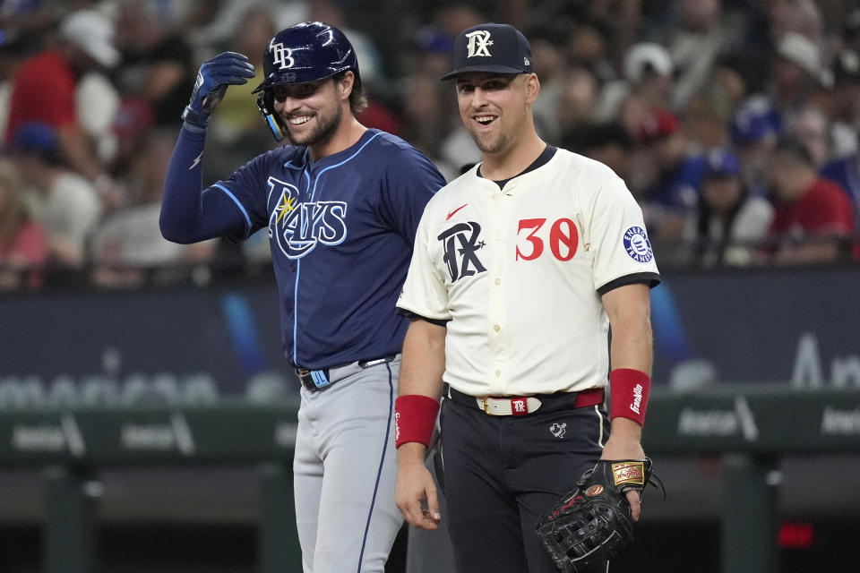 Texas Rangers first baseman Nathaniel Lowe (30) and his brother Tampa Bay Rays' Josh Lowe, left, laugh at first base after Josh singled during the sixth inning of a baseball game in Arlington, Texas, Friday, July 5, 2024. (AP Photo/LM Otero)