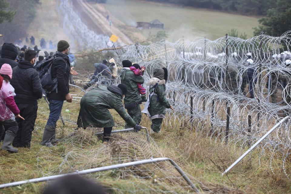 FILE - Migrants from the Middle East and elsewhere break down the fence as they gather at the Belarus-Poland border near Grodno, Belarus, Monday, Nov. 8, 2021. For most of his 27 years as the authoritarian president of Belarus, Alexander Lukashenko has disdained democratic norms, making his country a pariah in the West and bringing him the sobriquet of “Europe’s last dictator." Now, his belligerence is directly affecting Europe. (Leonid Shcheglov/BelTA via AP, File)