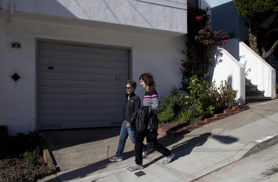 In this photo taken Monday, Nov. 12, 2012, Amy Cunninghis, left, and Karen Golinski, right, walk down a street near their home in San Francisco. All Golinski wanted was to enroll her spouse in her employer-sponsored health plan. Four years later, her request still is being debated. Because Golinski is married to another woman and she works for the federal government, her personal personnel problem has morphed into a multi-pronged legal attack by gay rights activists to overturn the 1996 law that defines marriage as the union of a man and a woman. (AP Photo/Eric Risberg)