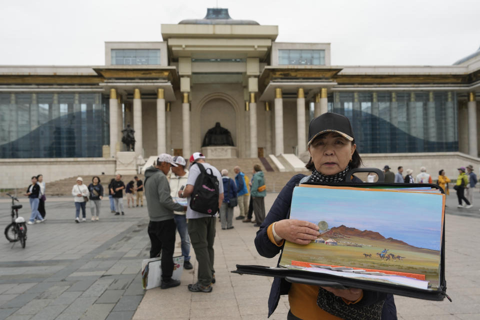 A woman hawks artwork depicting rural Mongolia on Sukhbaatar Square in Ulaanbaatar, Mongolia, Thursday, June 27, 2024. (AP Photo/Ng Han Guan)