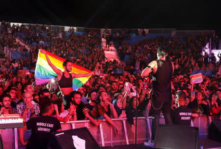 FILE PHOTO:A fan of Lebanese alternative rock band Mashrou' Leila holds a rainbow flag during their concert at the Ehdeniyat International Festival in Ehden town, Lebanon August 12, 2017. REUTERS/Jamal Saidi/File Photo