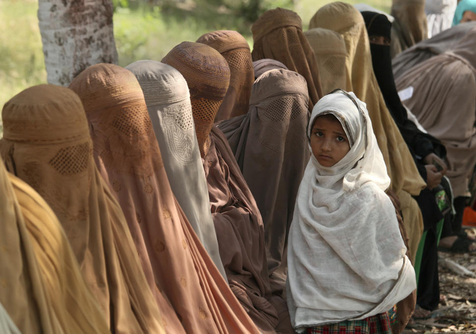 Women wait their turn to receive cash vouchers from an officer under the government's Ehsaas Emergency Cash program for families in need, in Peshawar, Pakistan, Tuesday, June 1, 2021. (AP Photo/Muhammad Sajjad)