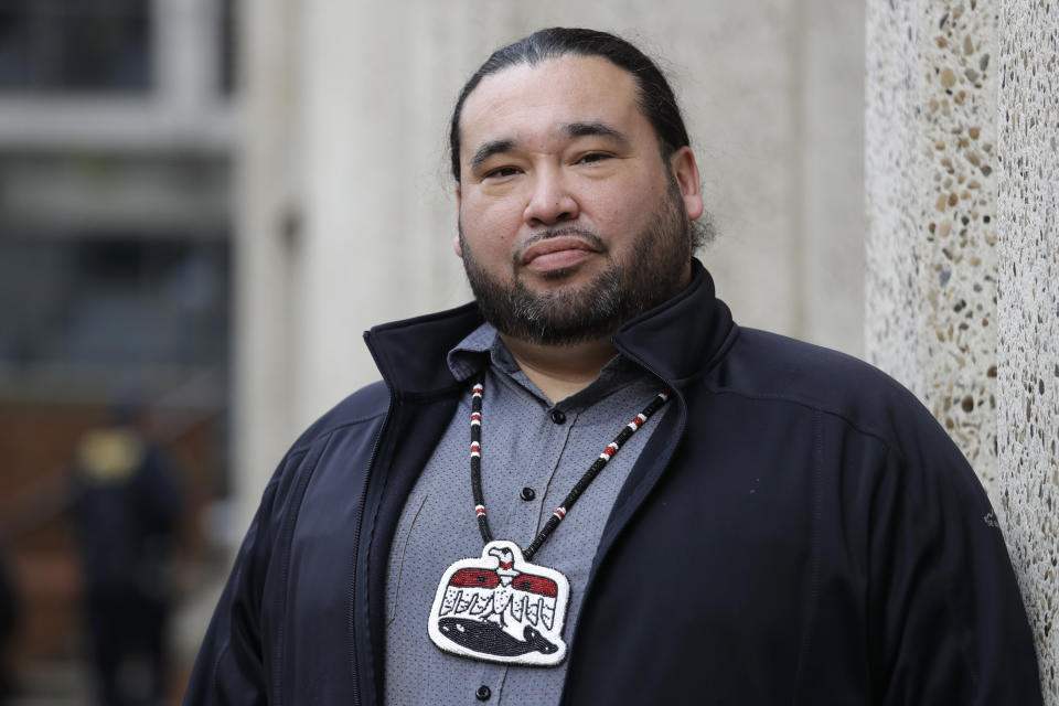 Makah Tribal Council Member Patrick DePoe poses for a photo before a federal court hearing to help determine whether his small American Indian tribe can once again hunt whales, Thursday, Nov. 14, 2019, in Seattle. The symbol he wears is from the tribes flag, and includes bird and whale symbols. The Makah Tribe, from the northwest corner of Washington state, conducted its last legal hunt in 1999, when its crew harpooned a gray whale from a cedar canoe. (AP Photo/Elaine Thompson)