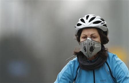 A cyclist wears a mask with an air filter as she cycles through Hyde Park in London April 3, 2014. REUTERS/Suzanne Plunkett