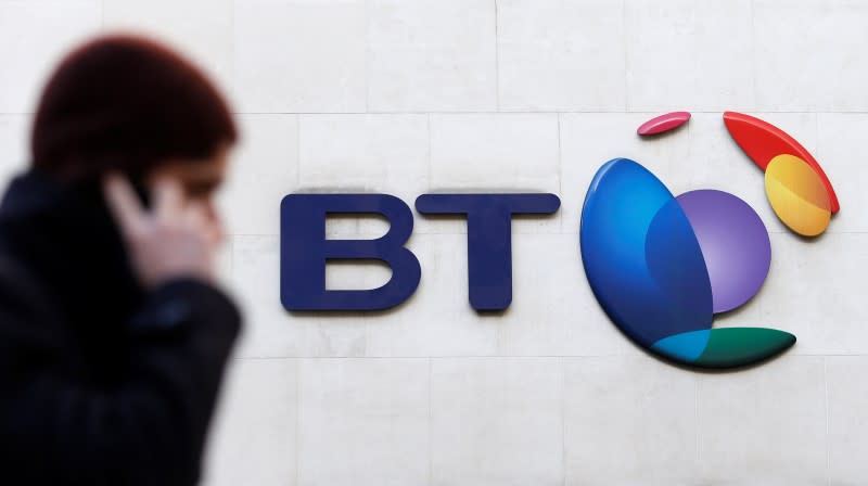 A man talks on his mobile telephone as he walks past a BT logo in London, February 5, 2015. REUTERS/Suzanne Plunkett