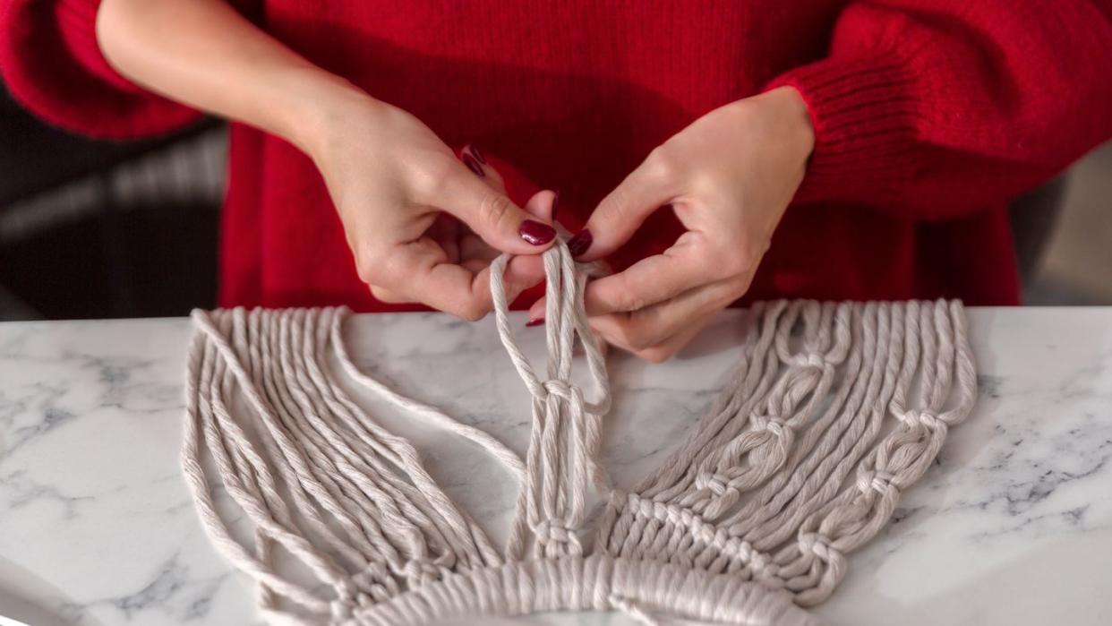 a person making knots on macrame project