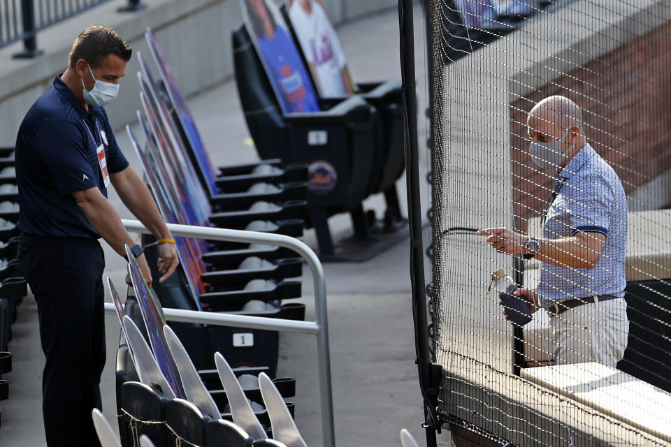 New York Yankees general manager Brian Cashman, right, talks with New York Mets general manager Brodie Van Wagenen prior to their baseball teams spring training game Saturday, July 18, 2020, in New York. (AP Photo/Adam Hunger)