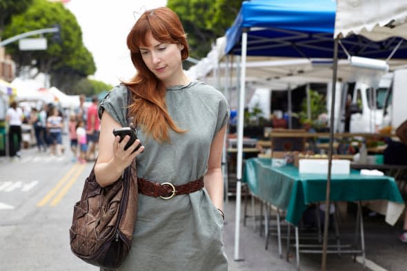 Mid adult woman looking at mobile phone in city