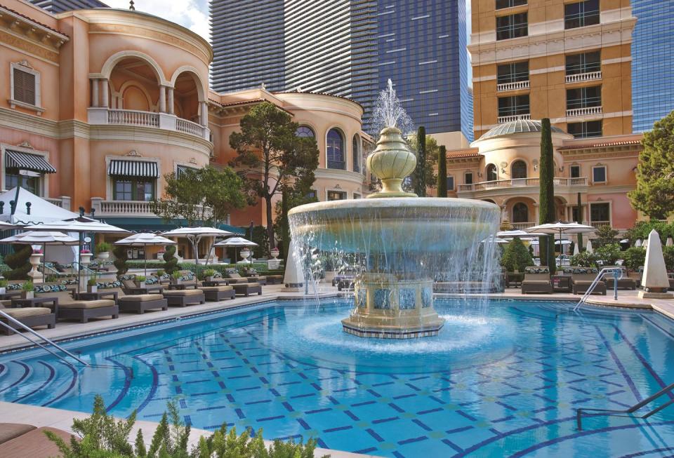 a fancy pool with a fountain in the middle and deck chairs all around