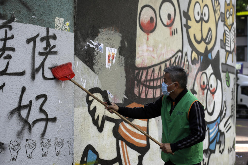A worker cleans up a vandalized wall Monday, Dec. 9, 2019, in Hong Kong. Hundreds of thousands of demonstrators crammed into Hong Kong's streets on Sunday, their chants echoing off high-rises, in a mass show of support for the protest movement entering its seventh month. (AP Photo/Kiichiro Sato)