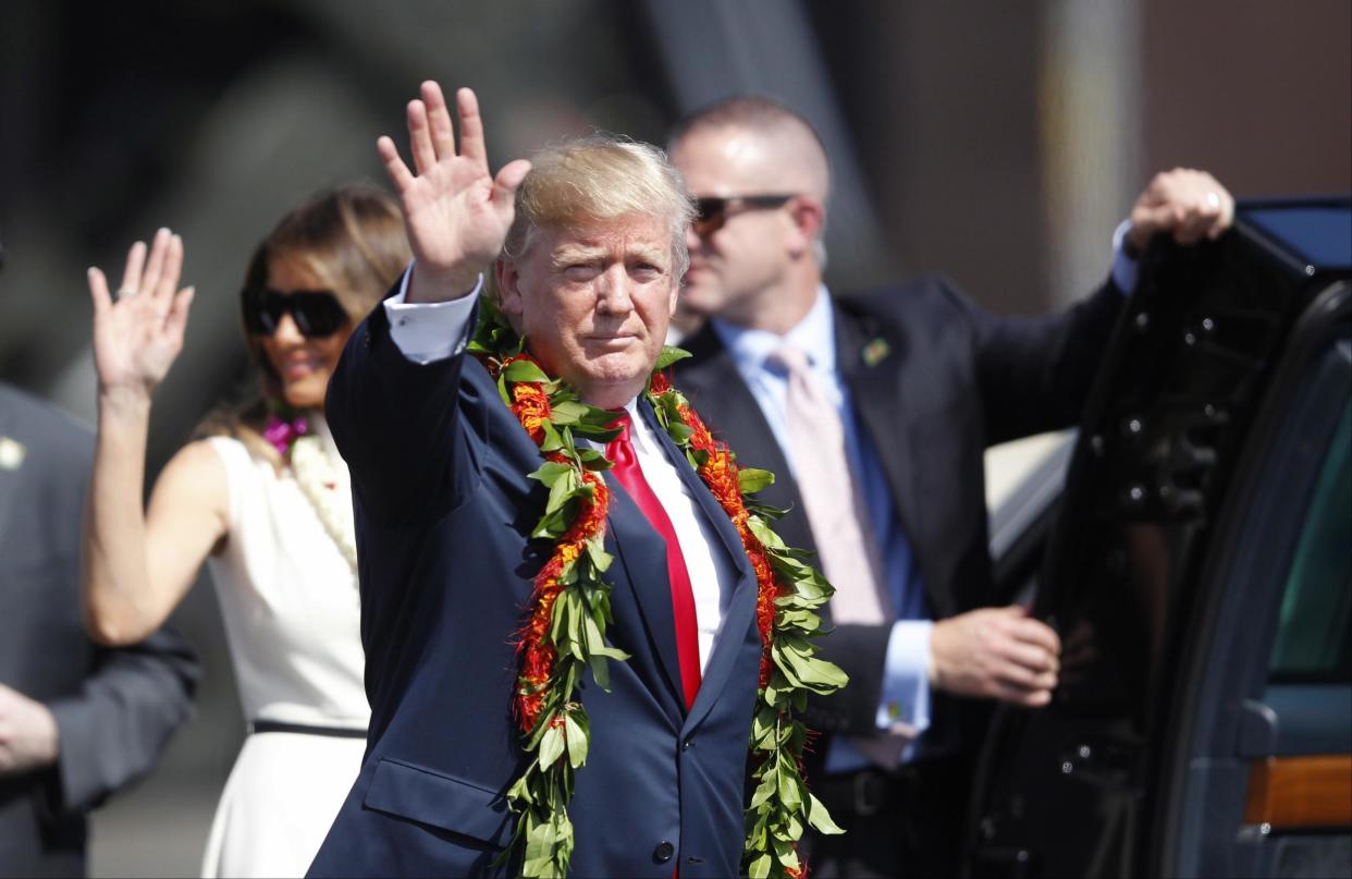 Adorned with lei, President Donald Trump walks towards the motorcade with first lady Melania Trump in Honolulu: Jamm Aquino/The Star-Advertiser via AP