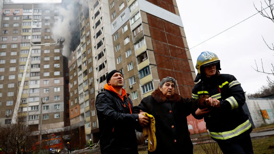Firefighters in Kyiv help a woman to leave a building damaged by Russian strikes. - Valentyn Ogirenko/Reuters