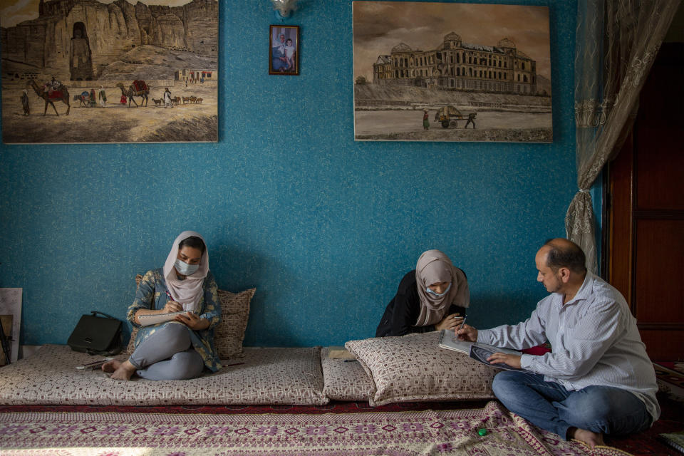 Akbar Farhad, an Afghan artist, teaches young Afghan refugees inside his rented accommodation in New Delhi, India on Aug. 17, 2021. Farhad has been living in New Delhi since 2018. He left Kabul after facing threats from insurgents demanding he close his studio. Like thousands of other Afghan refugees in India, their plans to someday return home were dashed by the Taliban's shockingly swift takeover of the country. (AP Photo/Altaf Qadri)