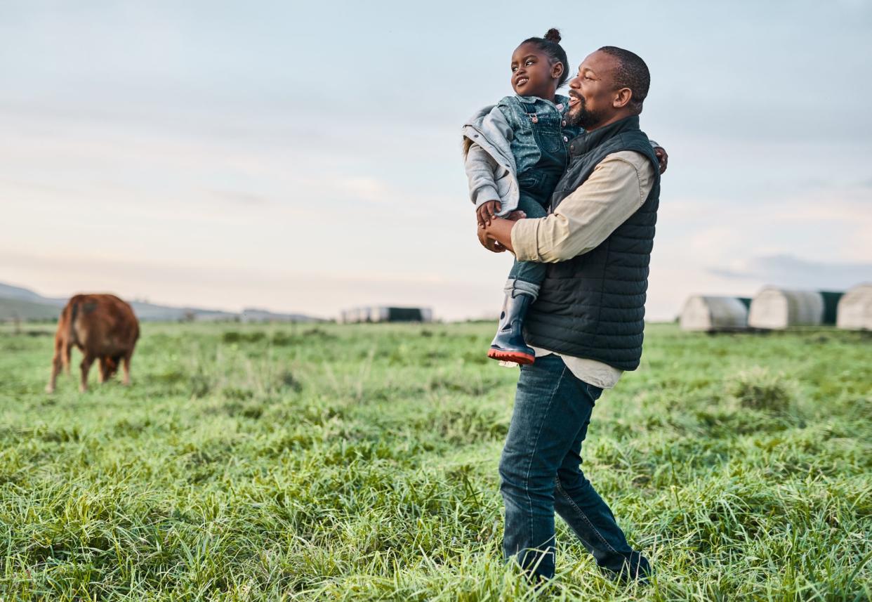 Shot of a mature man carrying his adorable daughter on a cow farm