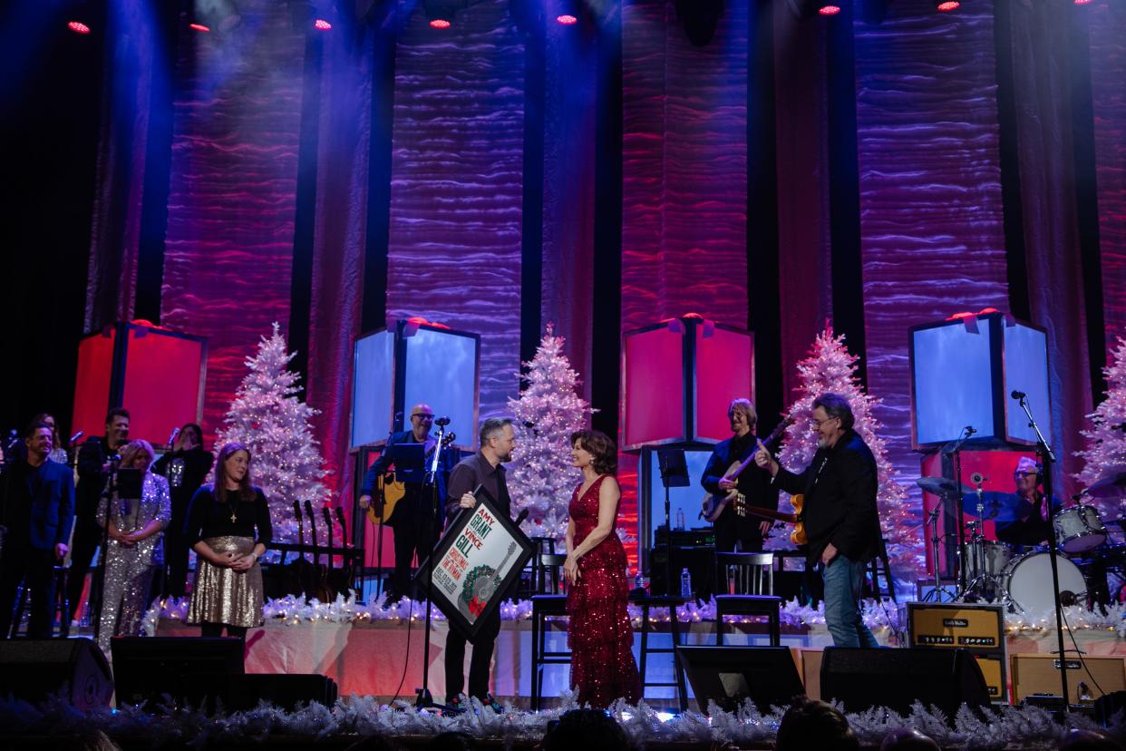 Amy Grant and Vince Gill presented with a Hatch Show Print by Nate Bargatze commemorating their 100th Christmas performance at the Ryman Auditorium
