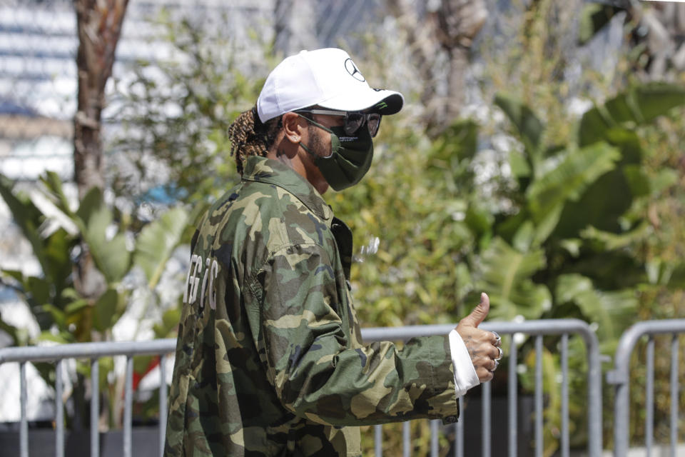 El británico Lewis Hamilton, piloto de Mercedes, saluda al ingresar en el paddock de Mónaco, el miércoles 19 de mayo de 2021 (AP Foto/Luca Bruno)