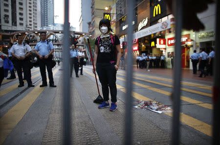 A pro-democracy protester takes a break as she sweeps a street after policemen removed some barricades, at a protest site at the commercial area of Causeway Bay in Hong Kong October 14, 2014. REUTERS/Carlos Barria