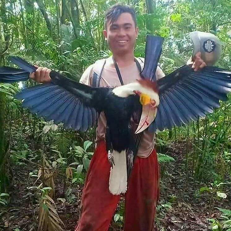 Photo of man posing with dead hornbill he hunted in Indonesia. 