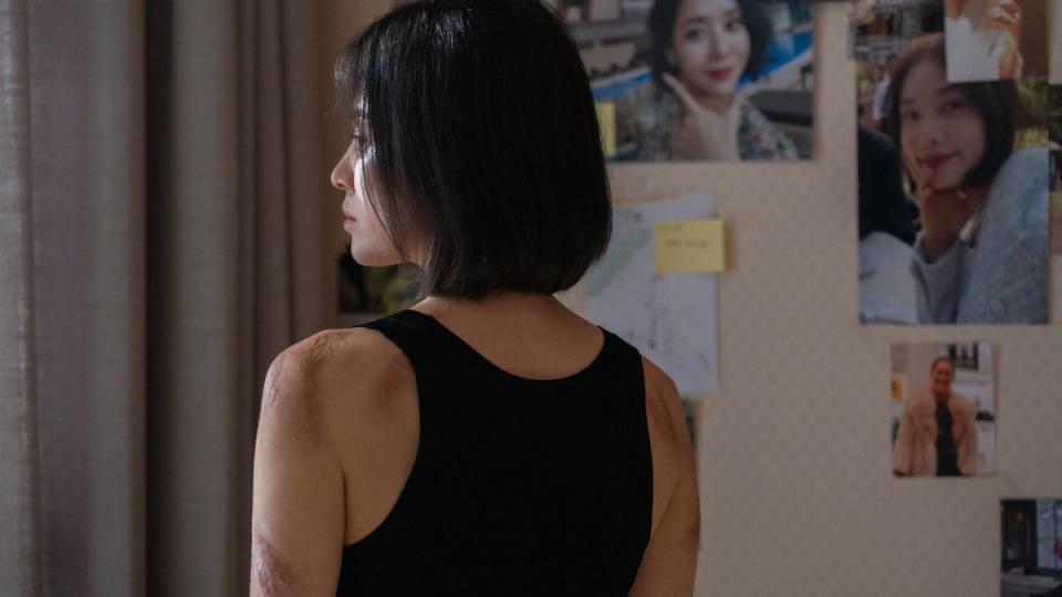 a woman with her back to the camera has visible burn scars from her childhood bullies in a scene from korean drama the glory