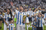 Argentina's Lionel Messi walks around the Monumental stadium with the FIFA World Cup trophy, accompanied by his Antonela Roccuzzo and children, during a celebration ceremony for local fans after an international friendly soccer match against Panama in Buenos Aires, Argentina, Thursday, March 23, 2023. (AP Photo/Gustavo Garello)
