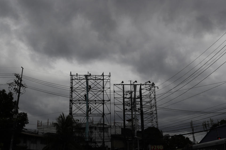 Dark clouds envelop the skies as workers fold a billboard to prepare for the coming of typhoon Vongfong in Manila, Philippines Thursday May, 14, 2020. The first typhoon to hit the country this year roared toward the eastern Philippines on Thursday as authorities work to evacuate tens of thousands of people while avoiding overcrowding in shelters that could spread the coronavirus. (AP Photo/Aaron Favila)