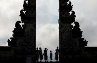 Balinese worshippers look at Mount Agung, enshrouded by clouds, from the gate of Penataran Agung Lempuyang temple, a day after the volcano's alert status was raised to the highest level, in Karangasem Regency, on the resort island of Bali, Indonesia September 23, 2017. REUTERS/Darren Whiteside