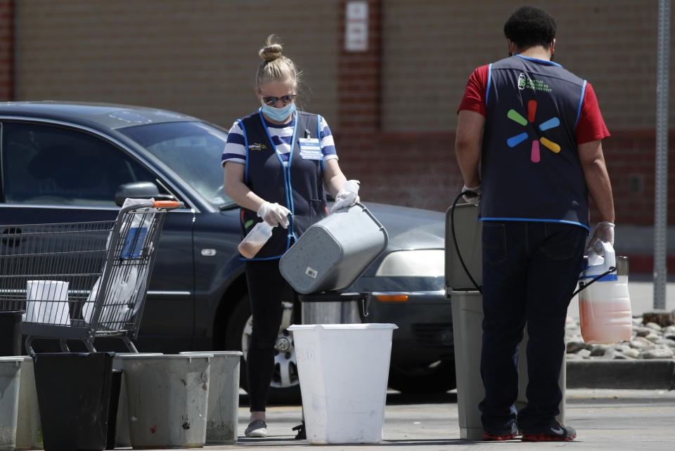 Workers sanitize items in the parking lot in front of a Walmart that has been closed following the deaths of three people connected to the store who were infected with the new coronavirus Friday, April 24, 2020, in Aurora, Colo. (AP Photo/David Zalubowski)