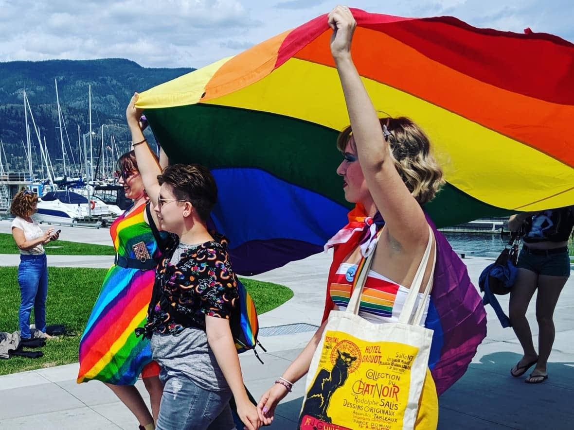 Pride parade participants march along Okanagan Lake in downtown Kelowna, B.C., on June 11. Four more communities in the Interior — Armstrong, 100 Mile House, Lillooet and Vanderhoof — are celebrating Pride this year. (Kelowna Pride/Facebook - image credit)