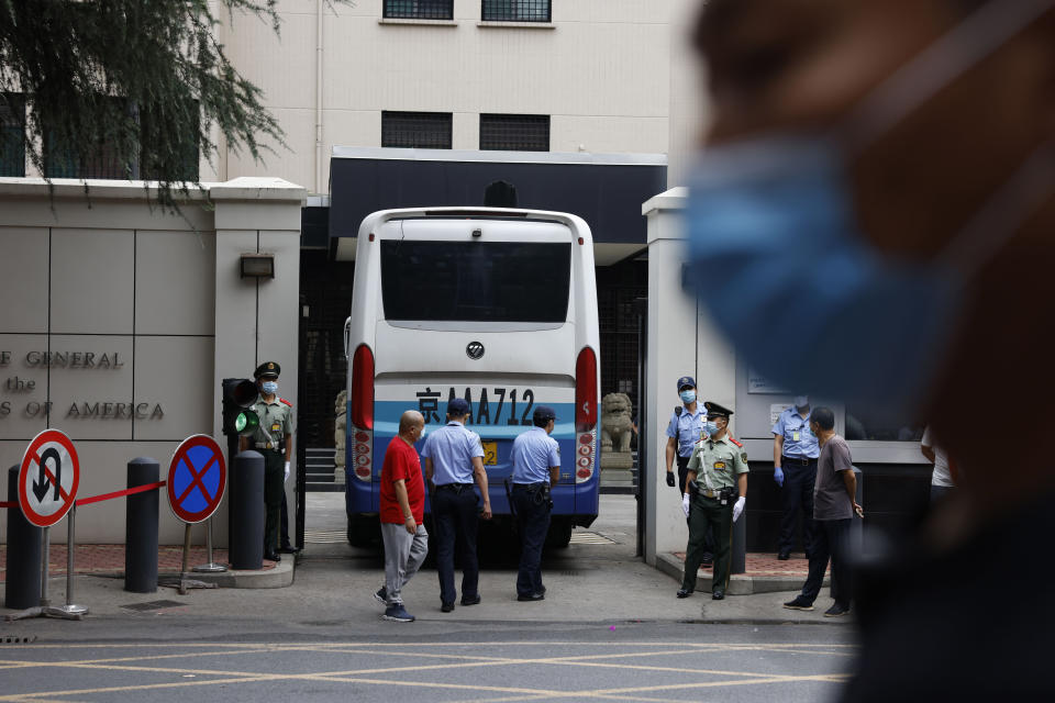 Chinese paramilitary policemen, in green, and consulate security, in blue, guard the gate as it opens to let a bus enter the United States Consulate in Chengdu in southwestern China's Sichuan province Saturday, July 25, 2020. China ordered the United States on Friday to close its consulate in the western city of Chengdu, ratcheting up a diplomatic conflict at a time when relations have sunk to their lowest level in decades. (AP Photo/Ng Han Guan)