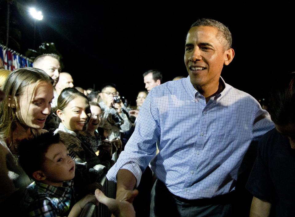 President Barack Obama greets people on the tarmac before boarding Air Force One at Honolulu Joint Base Pearl Harbor-Hickam, in Honolulu, Saturday, Jan. 4, 2014, as he travels back to Washington after their annual family vacation. (AP Photo/Carolyn Kaster)
