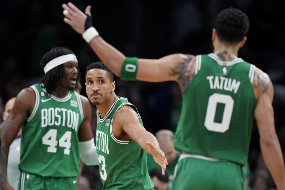 Boston Celtics guard Malcolm Brogdon, center, celebrates with forward Jayson Tatum (0) after their team scored while center Robert Williams III (44) looks on in the second half of an NBA basketball game against the Golden State Warriors, Thursday, Jan. 19, 2023, in Boston. (AP Photo/Steven Senne)