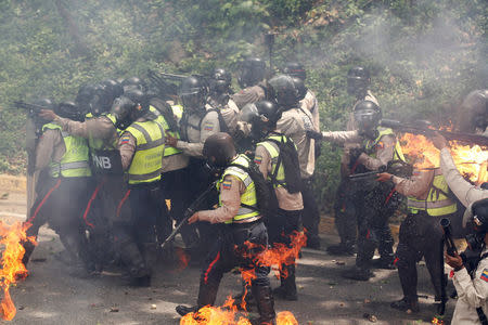 Riot police officers react to fire during a rally against Venezuela's President Nicolas Maduro in Caracas, Venezuela. REUTERS/Christian Veron