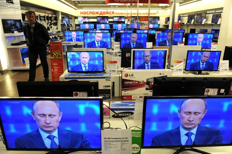 A customer walks past TV screens in a shop in Moscow, on April 25, 2013, during the broadcast of President Vladimir Putin's televised question and answer session. Russian government-funded TV channel RT faced a new controversy Thursday after taking an American journalist off air for launching into a diatribe against Russia's anti-gay legislation