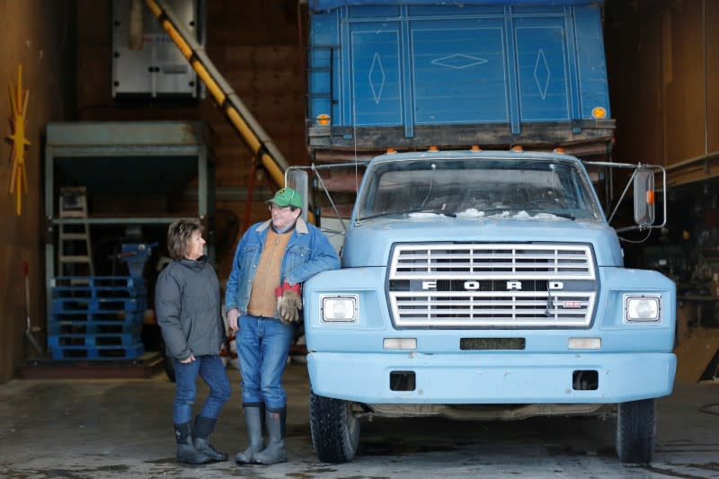 Farmer Steve Mackenzie-Grieve and his wife talk next to a grain truck in a barn at Yukon Grain Farm near Whitehorse