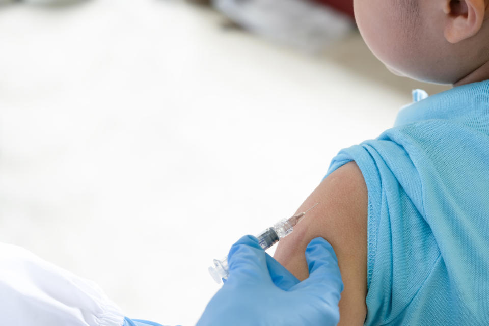 A doctor uses a syringe to administer a vaccine into a child's arm. (Photo via Getty Images)