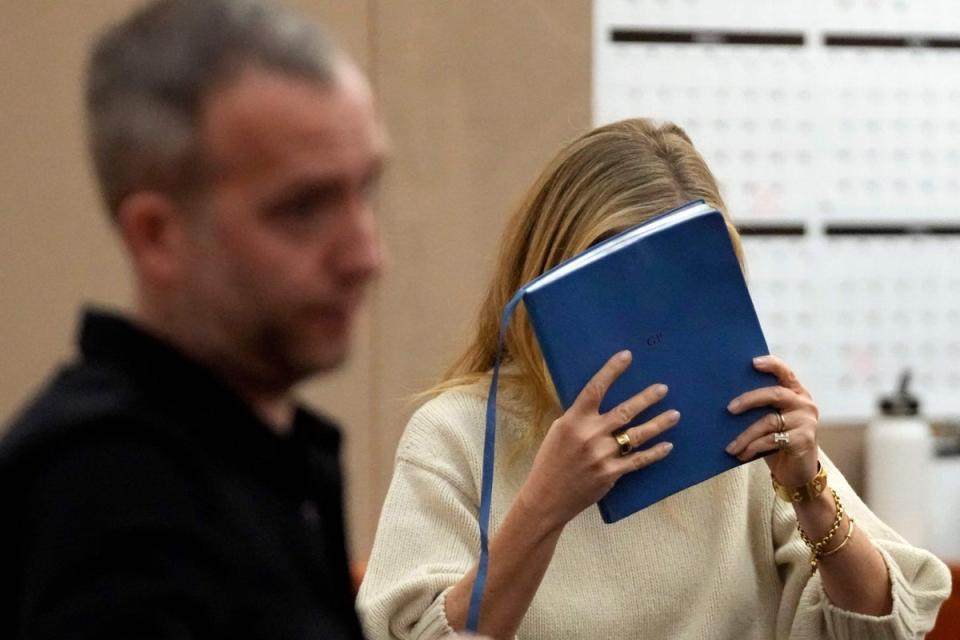 Ms Paltrow was seen hiding her face behind a blue notebook as she exited the room (AFP/Getty)