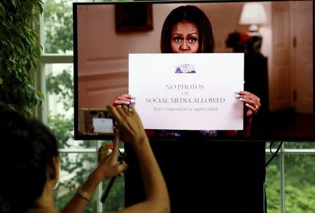 A video of U.S. first lady Michelle Obama getting rid of old signs prohibiting photography is shown as visitors can now take photos during tours of the White House in Washington July 1, 2015. REUTERS/Jonathan Ernst