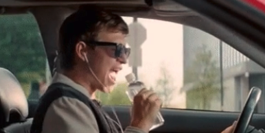 A man singing with a water bottle in his car