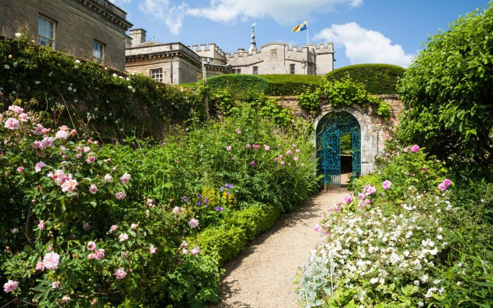 A glimpse of Rousham House from within the walled garden, with its wide herbaceous borders and gravel path - Andrew Baskott / Alamy Stock Photo 