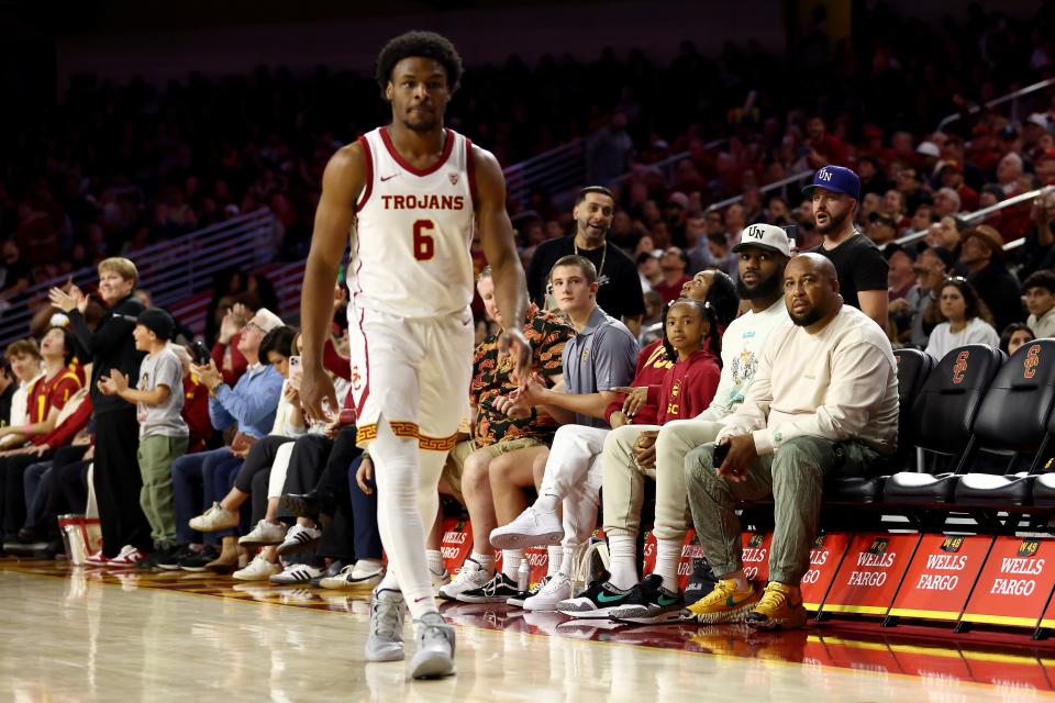 LOS ANGELES, CALIFORNIA - DECEMBER 10: LeBron James (2nd R) looks on from the stands towards Bronny James #6 of the USC Trojans during the first half against the Long Beach State 49ers at Galen Center. (Photo by Katelyn Mulcahy/Getty Images)