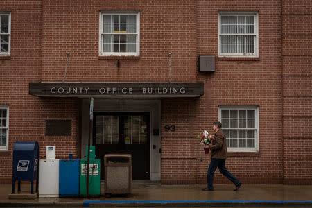 A man carries flowers outside a county office on Valentine's Day in Waynesburg, Pennsylvania, U.S., February 14, 2018. Picture taken February 14, 2018. REUTERS/Maranie Staab