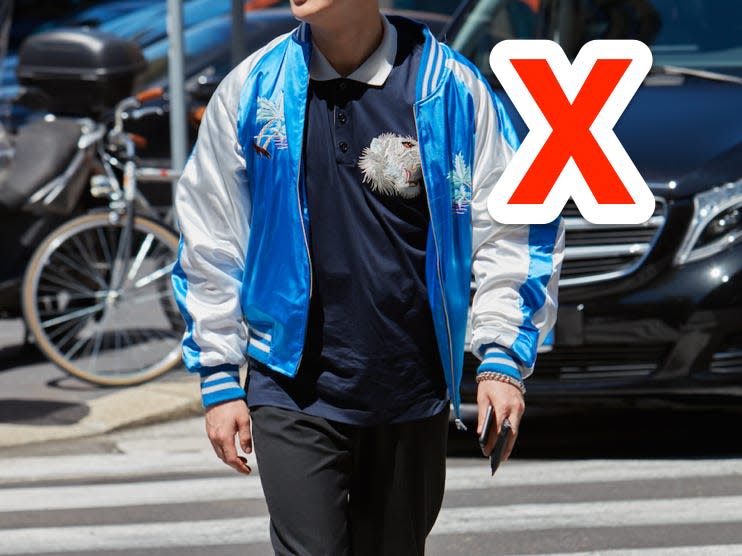 red x next to someone walking down street wearing black and navy outfit with blue and white bomber jacket